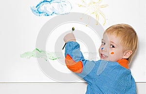 Little boy with brush covered in paint making funny face