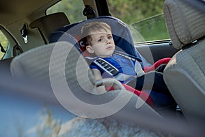 Little boy buckled up with seatbelt inside the car. Vehicle and transportation concept