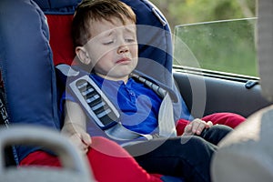 Little boy buckled up with seatbelt inside the car. Vehicle and transportation concept