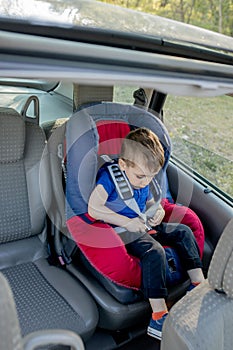 Little boy buckled up with seatbelt inside the car. Vehicle and transportation concept