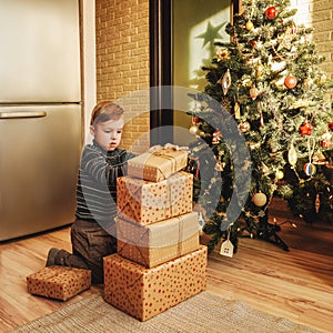 Little boy builds stack gift boxes home