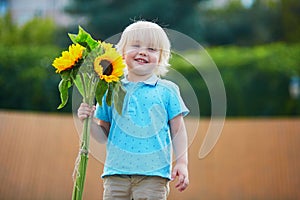 Little boy with bunch of sunflowers outdoors