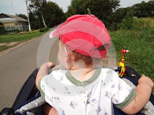 Little boy in cap explores street riding