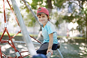 Little boy in cap sit on jungle gym