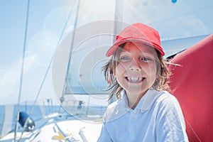 Little boy captain on board of sailing yacht on summer cruise. Travel adventure, yachting with child on family vacation. photo