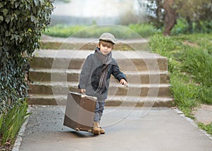 A little boy is carrying a big suitcase
