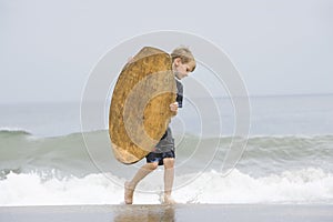 Little Boy Carrying Bodyboard In Sea