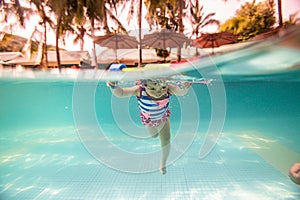 A little boy in a cartoon swimsuit is diving and playing in the swimming pool