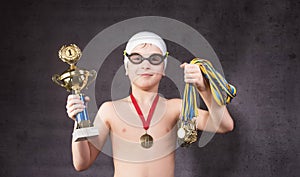 Little boy celebrates his golden trophy in swimming