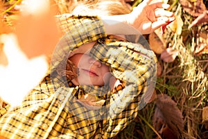 A little boy in a checkered shirt covers his eyes with his hands,