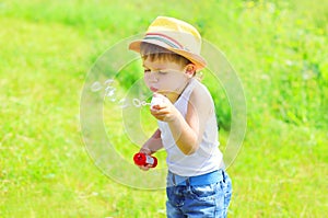 Little boy child blowing soap bubbles outdoors