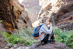 Little boy child eating sandwich while resting on mountain trail.