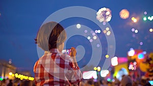 Little boy child filming pictures of beautiful fireworks in night sky display of mobile phone. Hands of baby taking