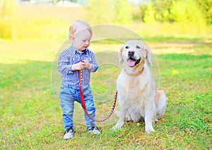 Little boy child with Golden Retriever dog on grass