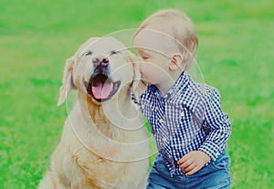 Little child and Golden Retriever dog together on a grass in a park