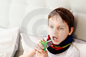 Little boy child inhaling his throat with spray inhaler