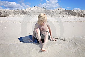 Little Boy Child Playin in the White Sand on the Beach at the Ocean