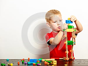 Little boy child playing with building blocks toys interior.