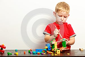 Little boy child playing with building blocks toys interior.