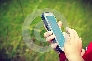 Little boy child playing games on mobile phone outdoor