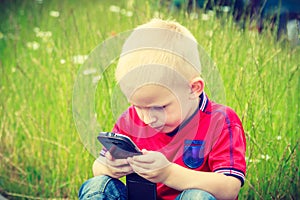 Little boy child playing games on mobile phone outdoor