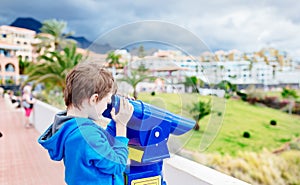 Little boy child playing with public pay telescope