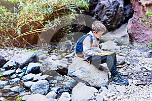 Little boy child reading map on mountain trail.