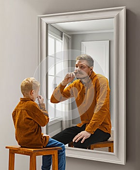 Little boy, child sitting near mirror and dreaming, imagining him being adult man. Conceptual collage. Age, past and