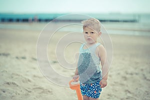 Little boy child standing with a wet shirt on the beach