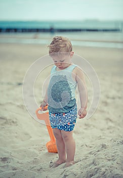Little boy child standing with a wet shirt on the beach