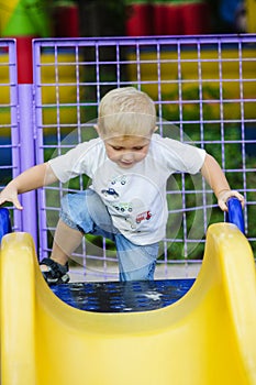 Little boy on a children's slide in the park on a walk