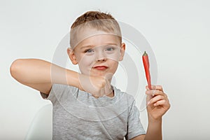 Little boy with chili pepper on white background. Extra hot cayenne pepper. Boy holding spicy red chili pepper. Portrait
