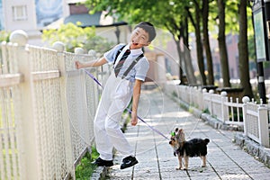 A little boy in China and his little Yorkshire dog stood in front of the fence.