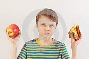 Little boy chooses between fastfood and healthy diet on white background