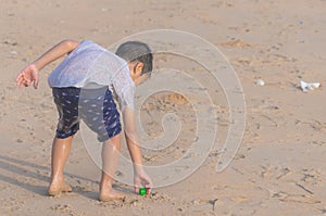 Little boy cleaning up garbage on the beach for enviromental clean up concept