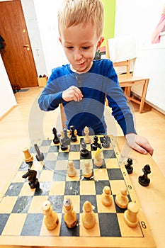 Little boy clever child playing chess thinking,