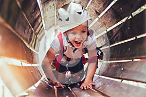 Little boy climbing in adventure activity park with helmet