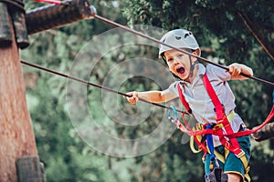Little boy climbing in adventure activity park with helmet