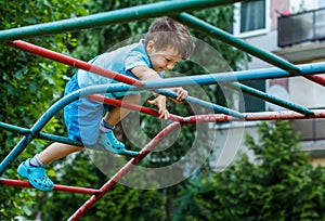 Little boy climbing on jungle gym without rope and helmet