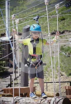 Little boy climbing on an outdoor ropes course