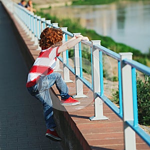 Little boy climbing over the fence