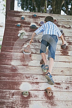 Little boy climbing a rock wall outdoor