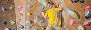 Little boy climbing a rock wall in special boots. indoor BANNER, LONG FORMAT