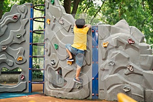 Little boy climbing on the rocks wall at playground