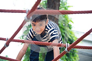 Little boy climbing rope at playground