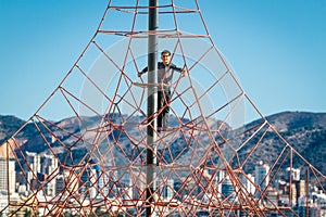 Little boy climbing on the rope at playground in Benidorm beach