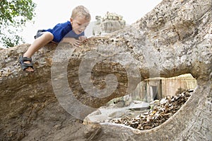 Little Boy Climbing on Tree Roots in Ruins