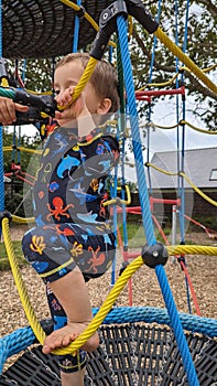 A little boy climbing up a rope ladder climbing frame netting