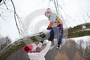 Little boy climbs down tree branch and mother