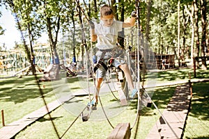 Little boy climbs in rope park at sunny day